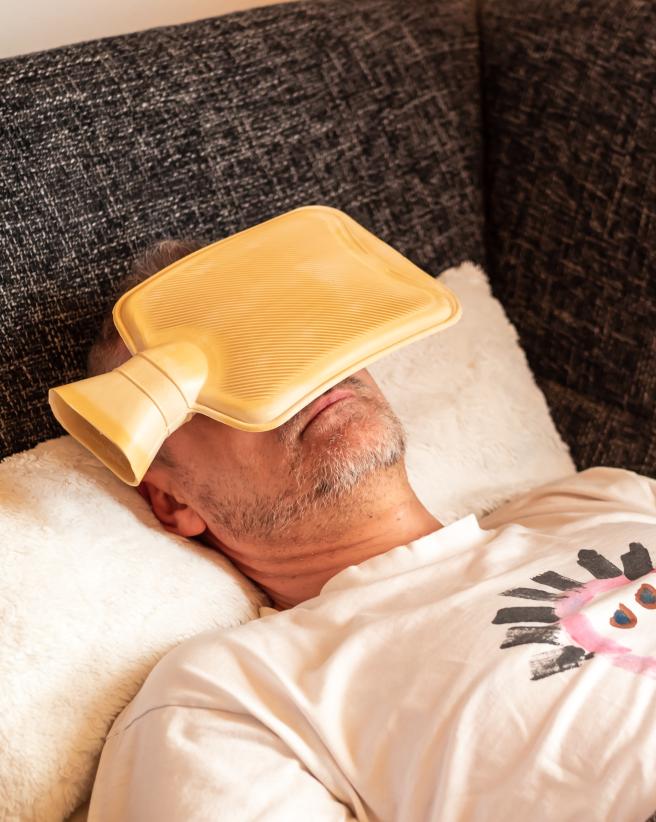 Man lying down with hot water bottle on his head