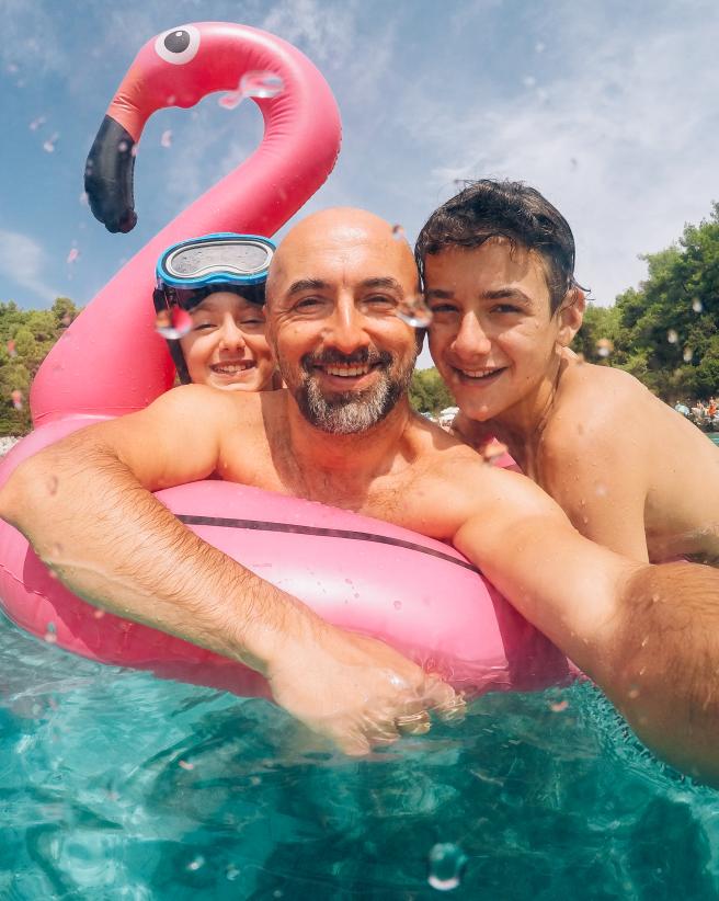 Man and two children in a pool on a flamingo floatie