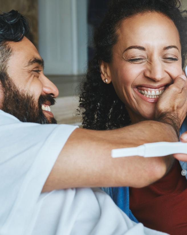 Couple smiling while looking at a pregnancy test