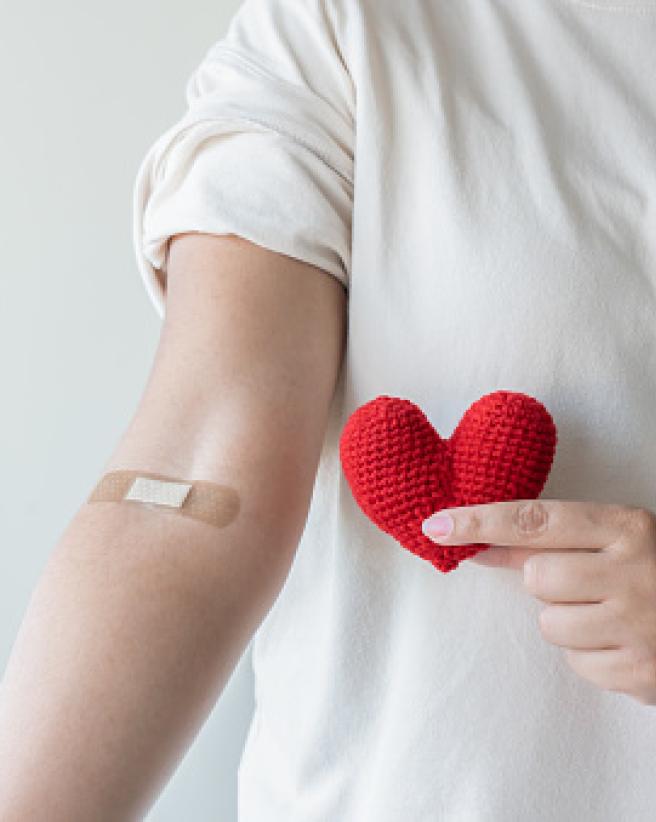 Person with bandage on inside of elbow after blood test