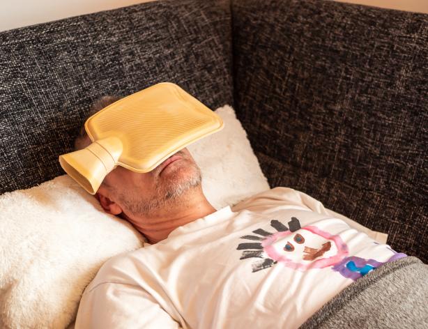 Man lying down with hot water bottle on his head