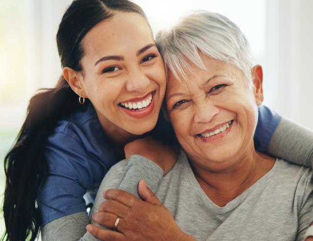 Home health aid hugging older woman from behind