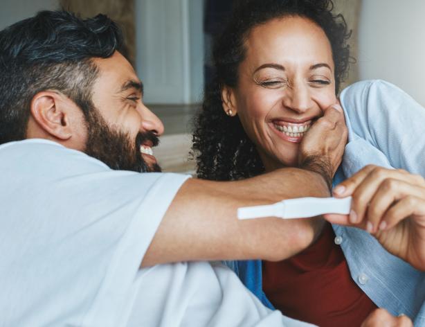 Couple smiling while looking at a pregnancy test